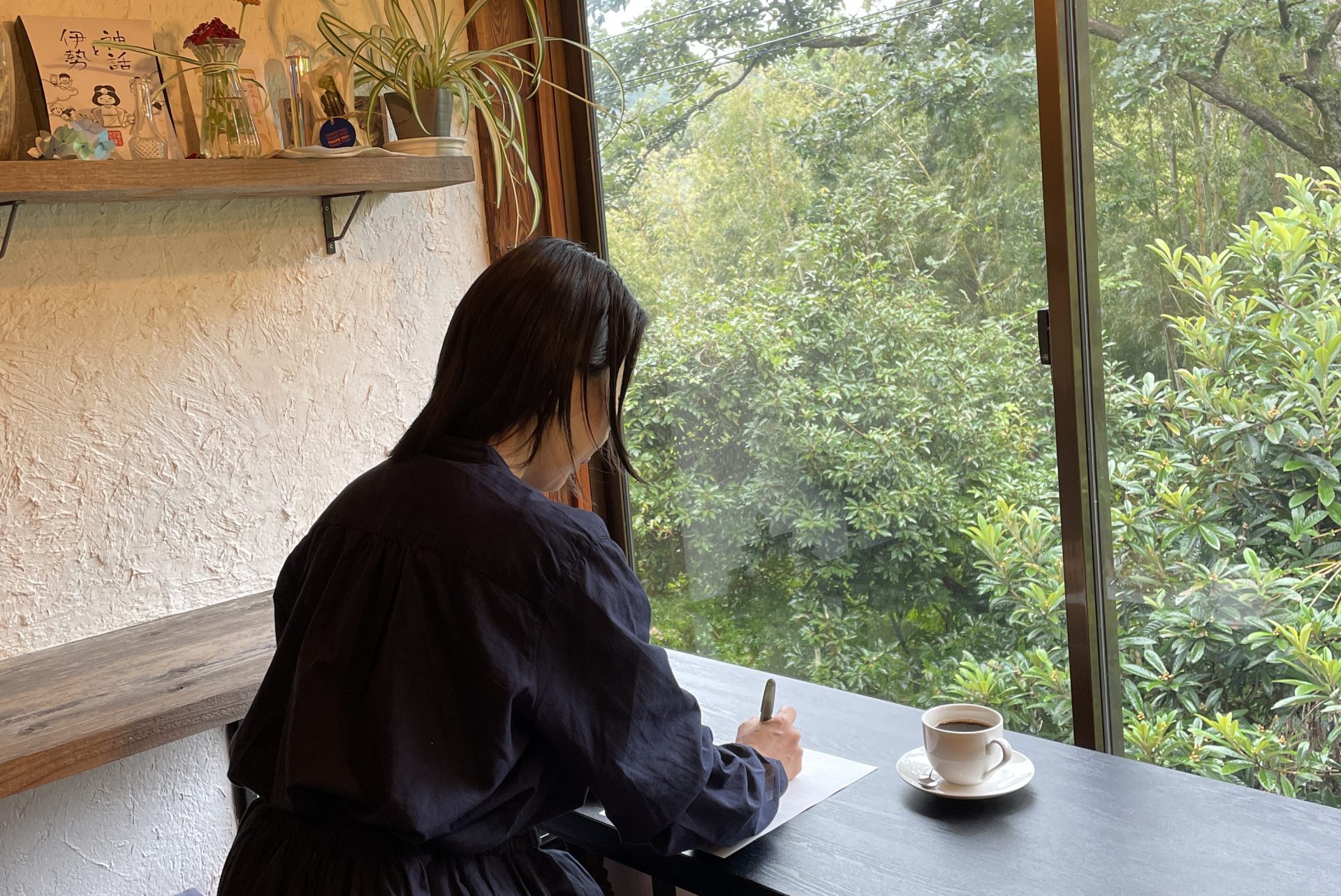 窓辺で手紙を書く女性の後ろ姿